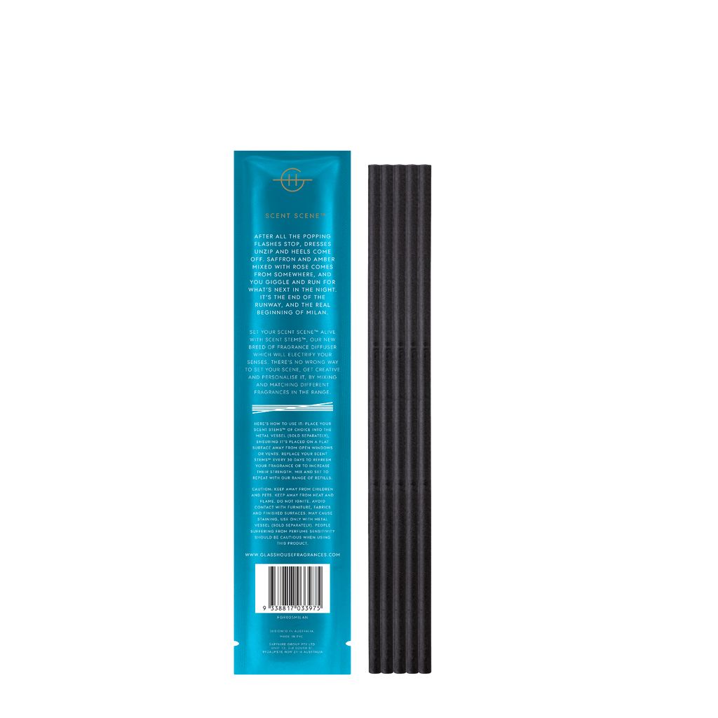 A turquoise rectangular package labeled Glasshouse Fragrances - Midnight In Milan Replacement Scent Stems sits beside a row of vertically stacked black sticks, detailing fragrance refills with hints of saffron and rose for an aromatic experience.