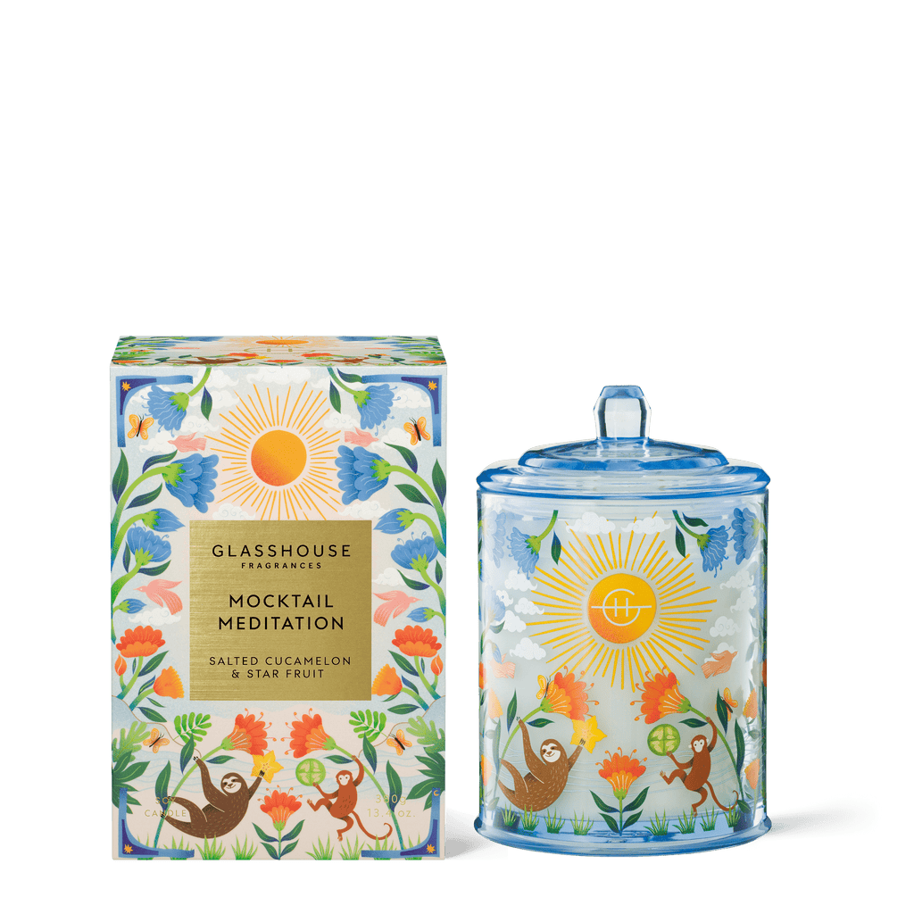 The Glasshouse Fragrances - Mocktail Meditation 13.4oz Candle comes in a decorative jar and box with colorful floral and sloth artwork, scented with Salted Cucumber & Star Fruit.