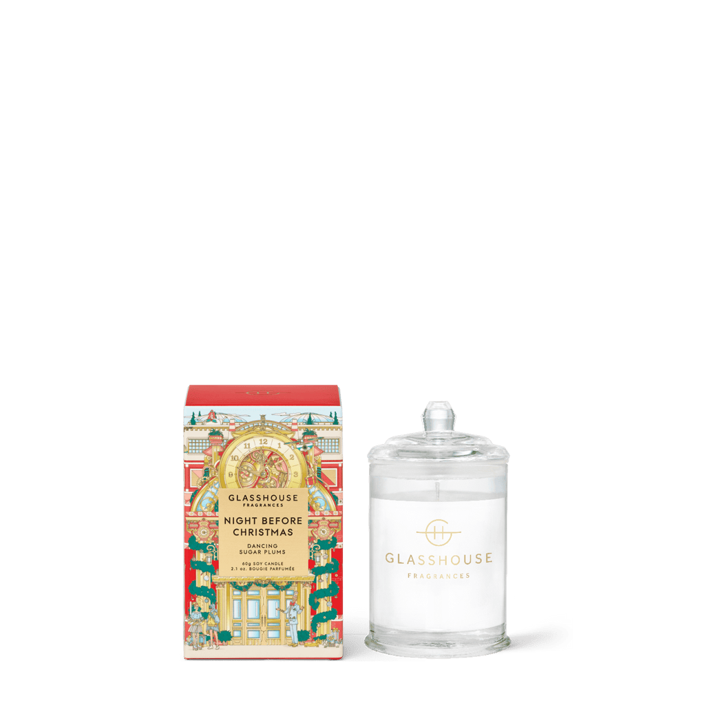 The Glasshouse Fragrances - Night Before Christmas 2.1oz Candle is shown beside its festive box with gold accents. The soy blend wax candle comes in a clear glass jar with a lid and gold logo, perfect for the holidays.