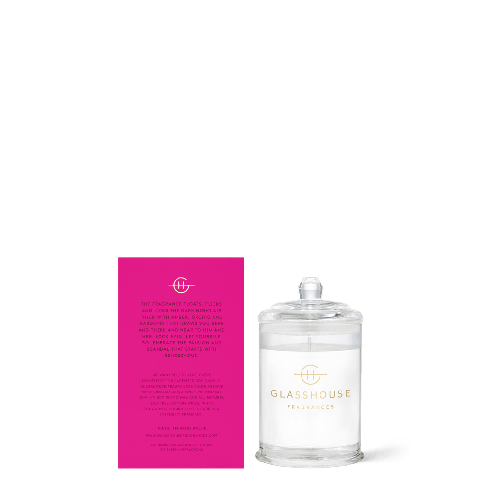 The Glasshouse Fragrances Rendezvous Mini Candle, crafted in Australia with a non-toxic soy blend wax, features a minimalist design in clear glass with a domed lid. Next to it is a pink card with gold fragrance notes.