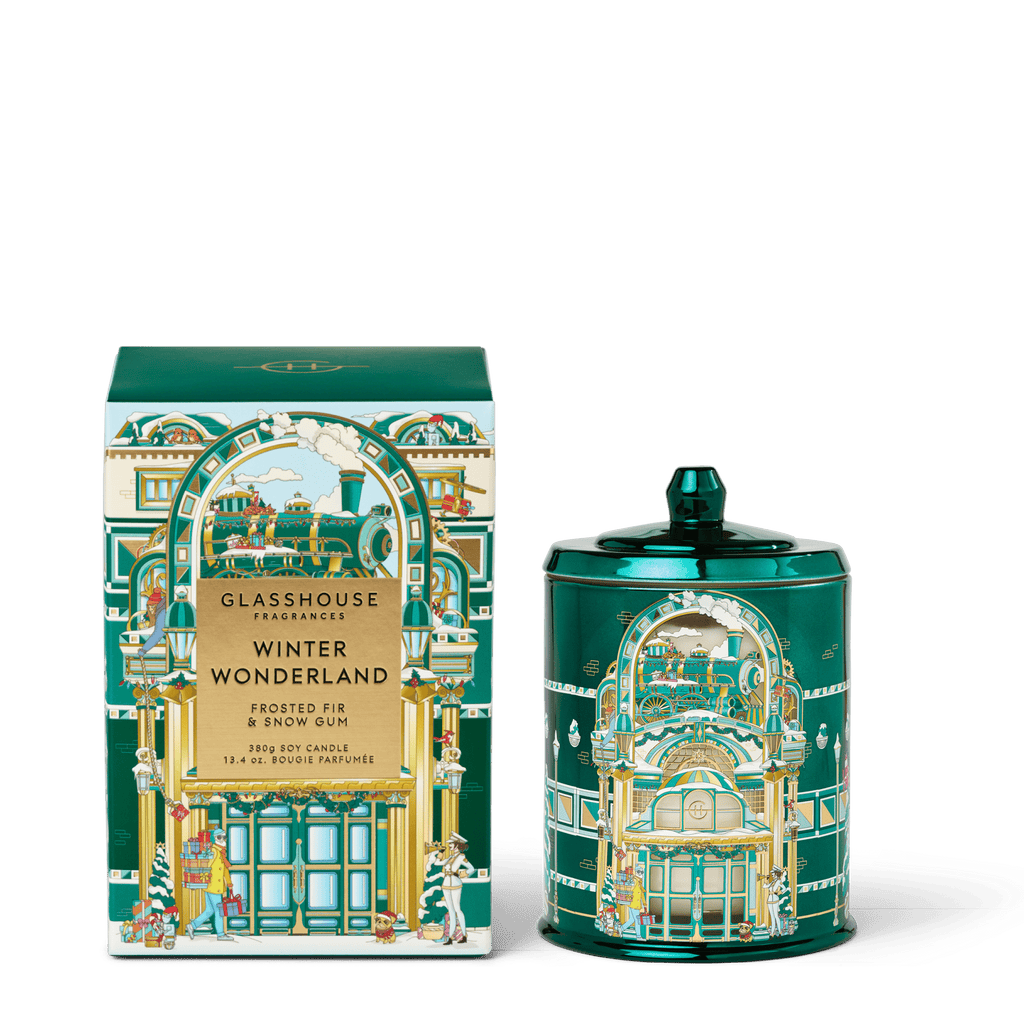 The Glasshouse Fragrances - Winter Wonderland 13.4oz Candle features festive train station illustrations on a lidded green jar and matching box. Made from a triple-scented soy blend wax by Glasshouse Fragrances.