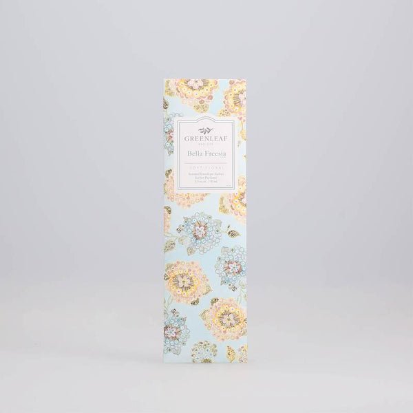 A rectangular box with a pastel floral pattern holds sachets. The front label reads Greenleaf - Bella Freesia Sachet, hinting at the delicate fragrance within.