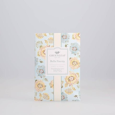 A floral packet features pastel flowers on a light blue background. The label reads Greenleaf - Bella Freesia Sachet, indicating the delicate fragrance inside.