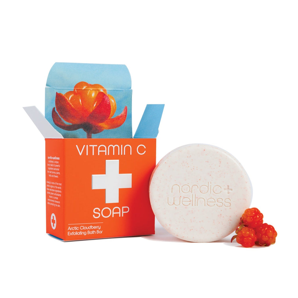 An open orange box of Kalastyle - Nordic+Wellness Vitamin C Soap Bar reveals an Arctic cloudberry illustration, with a round white soap bar embossed Nordic Wellness, enriched with Arctic cloudberry extract, alongside two fresh cloudberries.