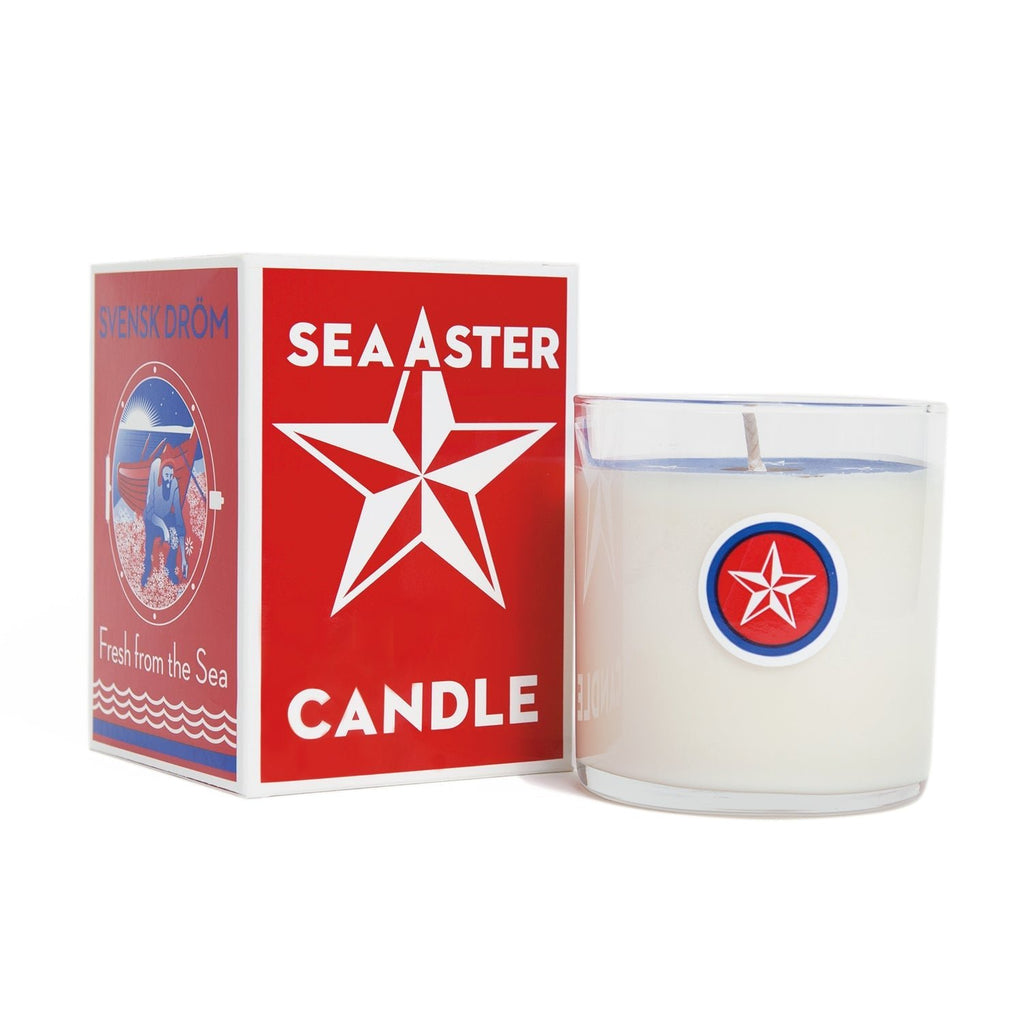 A white Kalastyle - Sea Aster Candle in a red star logo glass is beside its matching box. The red box with Sea Aster Candle in white text and a boat illustration holds the signature soy wax scent.