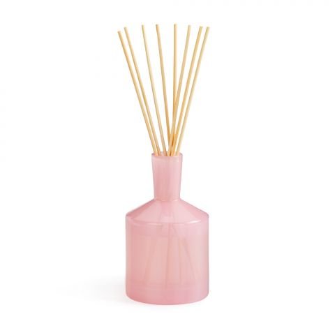 The Lafco - Blush Rose 6oz Reed Diffuser features a translucent pink glass bottle resembling a damask rose, with slender light brown reeds elegantly extending from its narrow neck against a plain white background.