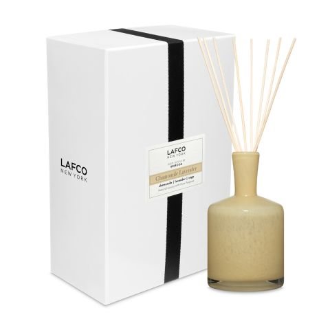 The Lafco - Chamomile Lavender 15oz Reed Diffuser features a beige bottle and reed sticks in a rectangular white box with black ribbon and label. It elegantly blends soothing chamomile and lavender scents for optimal fragrance diffusion.