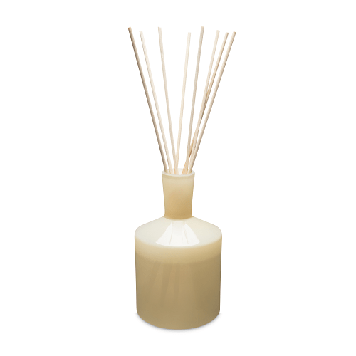 The Lafco - Chamomile Lavender 6oz Reed Diffuser, featuring a beige cylindrical base and slender wooden reeds, offers essential oil fragrances. Its simple elegance enhances the ambiance of any home or office.