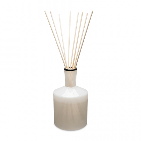 The Lafco - Champagne 6oz Reed Diffuser, featuring a narrow-necked white ceramic bottle with long reed sticks, exudes elegance against a plain white background. It releases essential oil-based fragrances with refreshing notes of grapefruit.