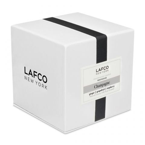 A white square box with a black vertical stripe and the Lafco New York label contains the Lafco - Champagne Signature 15.5oz Candle. This exquisite soy wax candle has a Champagne scent featuring notes of ginger, grapefruit, and raspberry.