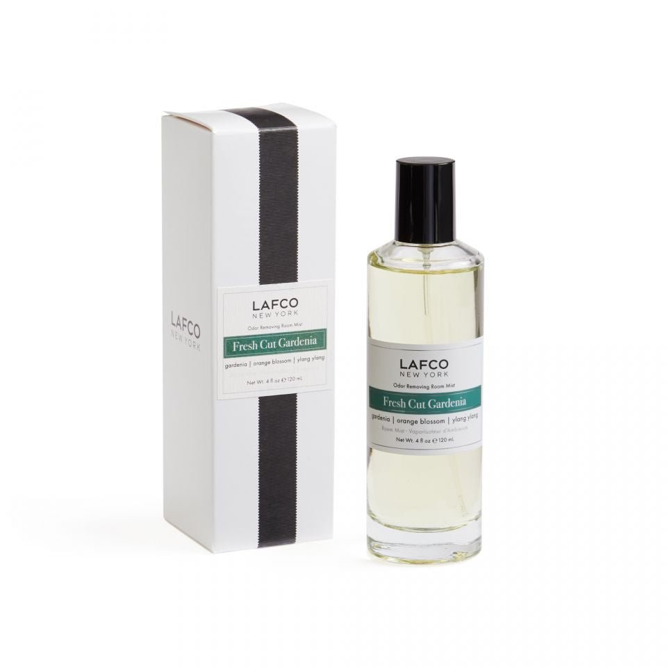 A clear bottle of Lafco - Fresh Cut Gardenia Room Mist with a black cap sits next to its white box accented by a black vertical stripe, containing light yellow liquid for refreshing, odor-removing fragrance.