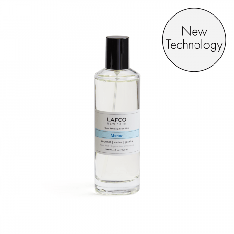 A clear glass bottle of Lafco - Marine Room Mist with a black cap and label sits beside a New Technology graphic on a white background. This room mist features an odor-removing marine fragrance ideal for any space.