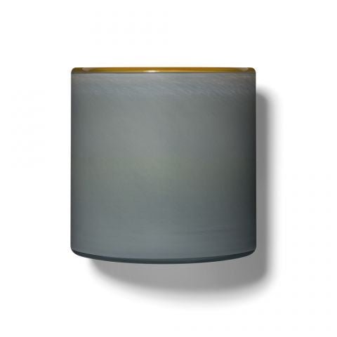 The Lafco - Sea & Dune Signature 15.5oz Candle features a cylindrical, grayish-blue hand blown glass cup with a faint yellow rim and smooth surface, casting a soft shadow against a white background.