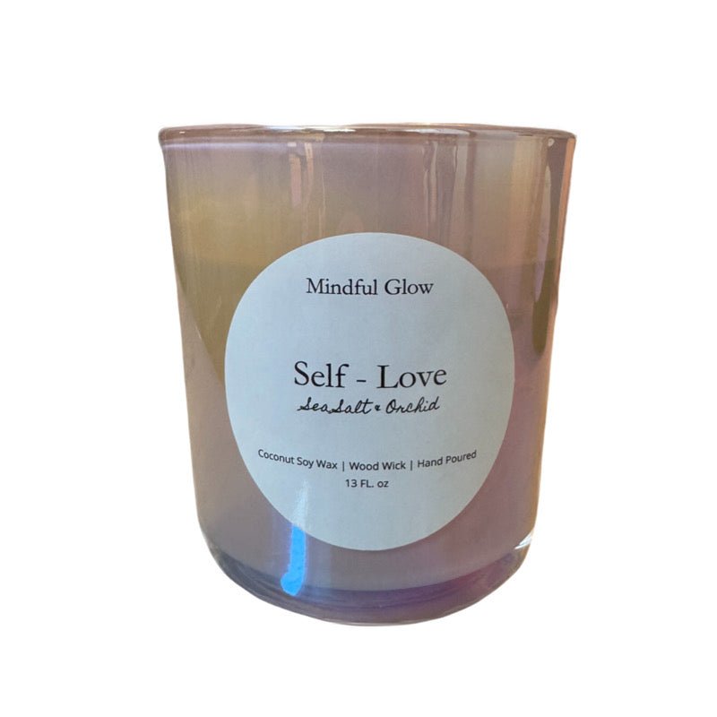 The Mindful Glow - Self Love Woodwick Candle 13oz features a pastel design, round white label, coconut soy wax, wood wick, is hand-poured, and scented with Sea Salt & Orchid.
