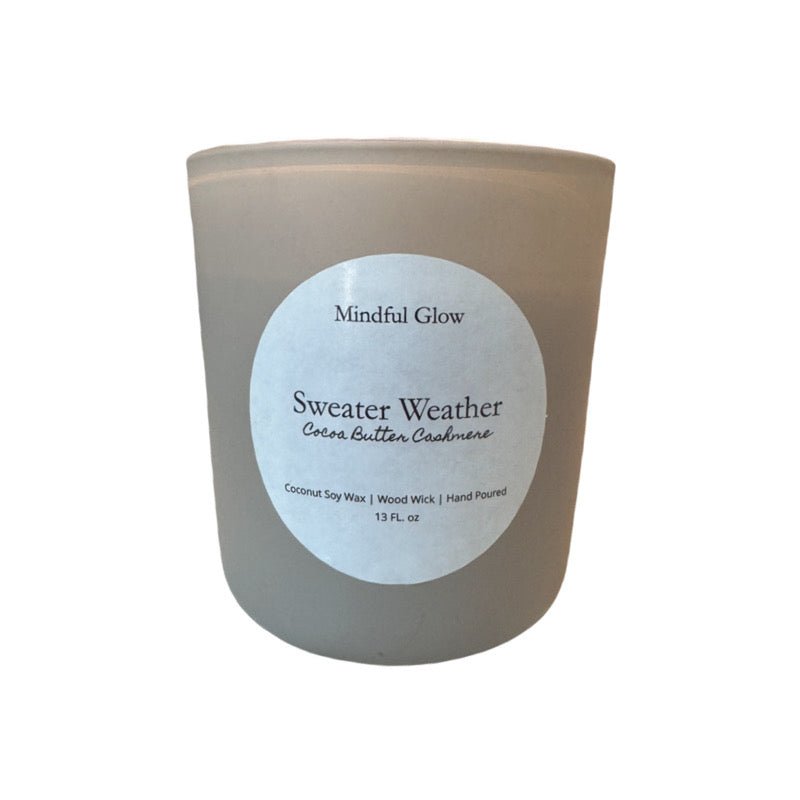 The Mindful Glow - Sweater Weather Woodwick Candle 13oz by Mindful Glow features coconut soy wax in a frosted glass jar with a wood wick, offering cozy Cocoa Butter Cashmere aroma—ideal for relaxation and comforting moments.