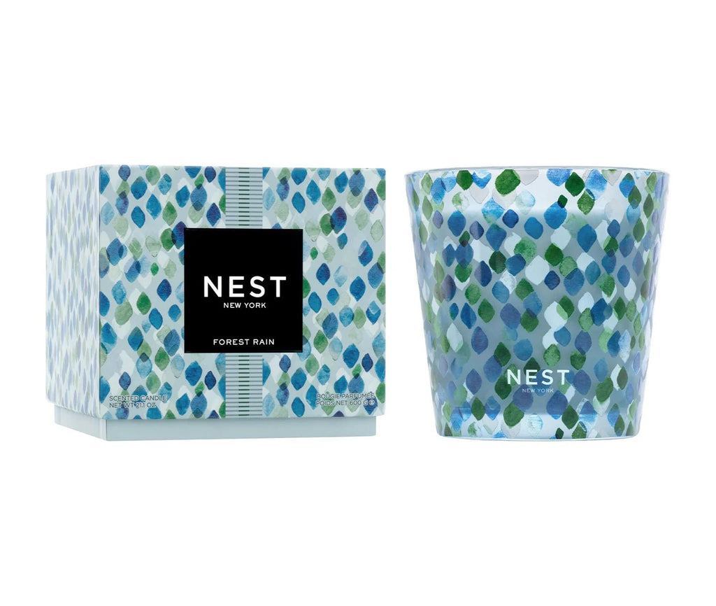 The Nest Forest Rain Decorative 3-Wick Candle features a blue and green leaf-patterned glass holder and comes with a matching box. Enjoy its clean burn and elegant style by Nest in any room.