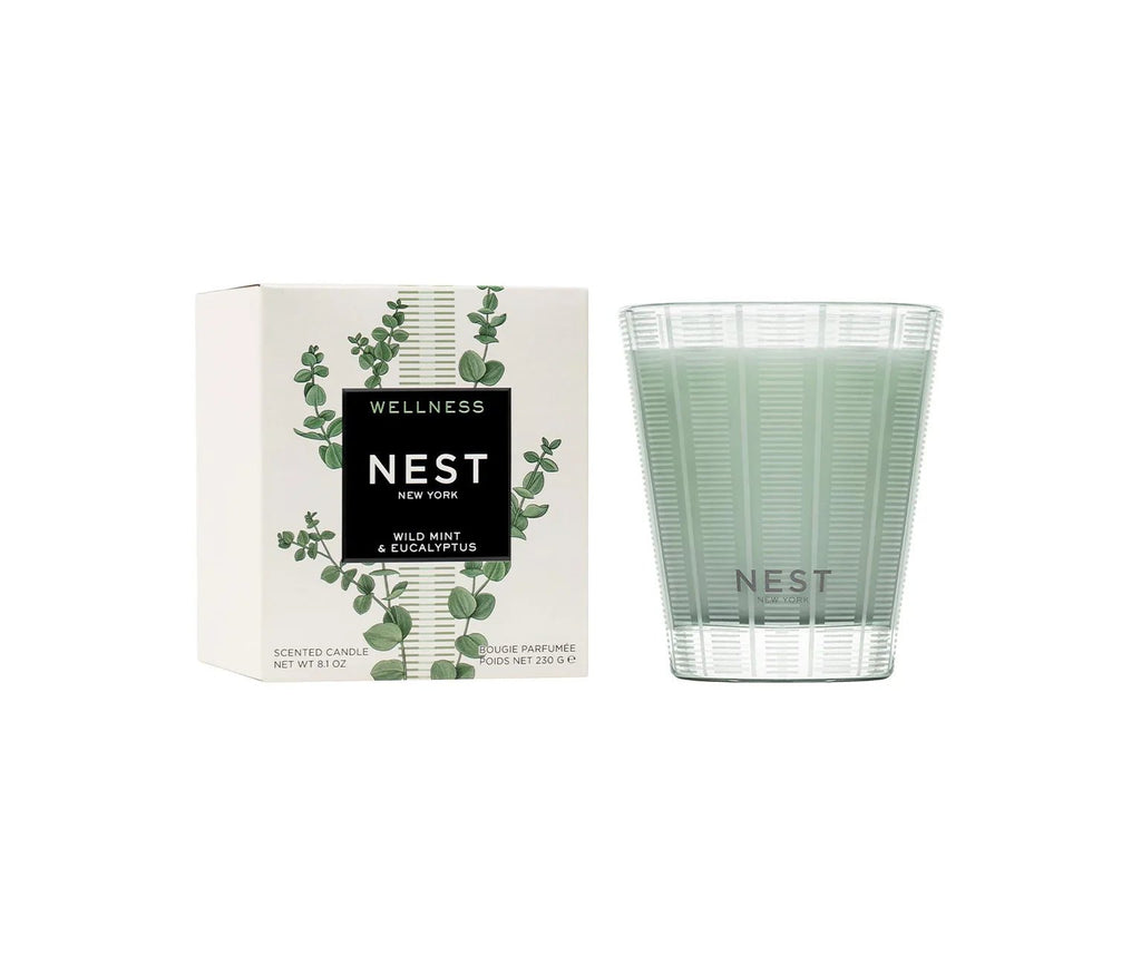 The Nest - Wild Mint & Eucalyptus Classic Candle sits next to its matching box adorned with eucalyptus leaves, delivering a refreshing aromatic experience with premium wax.