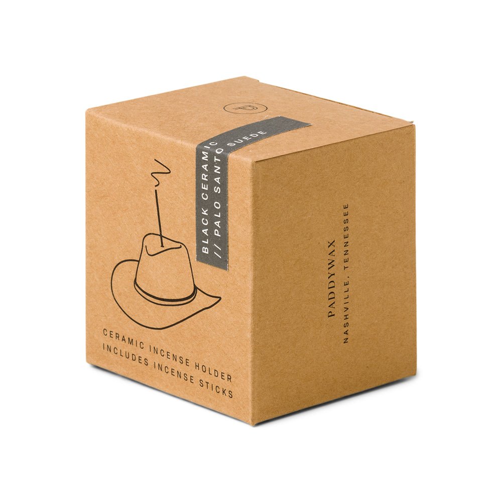 A brown cardboard box features a Western-themed cowboy hat illustration with incense smoke, labeled Paddywax - Black Cowboy Hat Ceramic Incense Holder // Palo Santo Suede scent. It reads Paddywax, Nashville, Tennessee, and contains a Cowboy Hat Incense Holder with sticks.