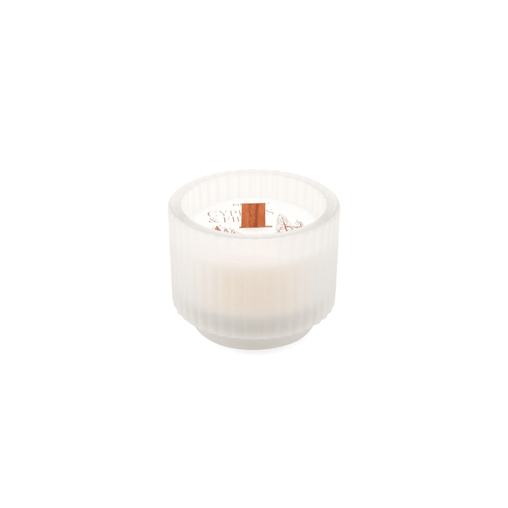 The Paddywax Cypress & Fir candle features a 5oz frosted white ribbed glass holder with an elegant circular design, housing a white candle with a crackling wood wick and the aroma of cypress and fir.