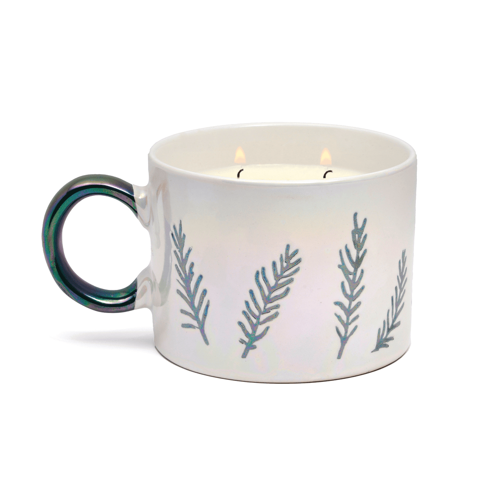 The Paddywax Cypress & Fir White Ceramic Mug Candle is a dual-purpose gift featuring two lit wicks, a dark green handle, and embossed teal botanical patterns resembling cypress and fir branches.