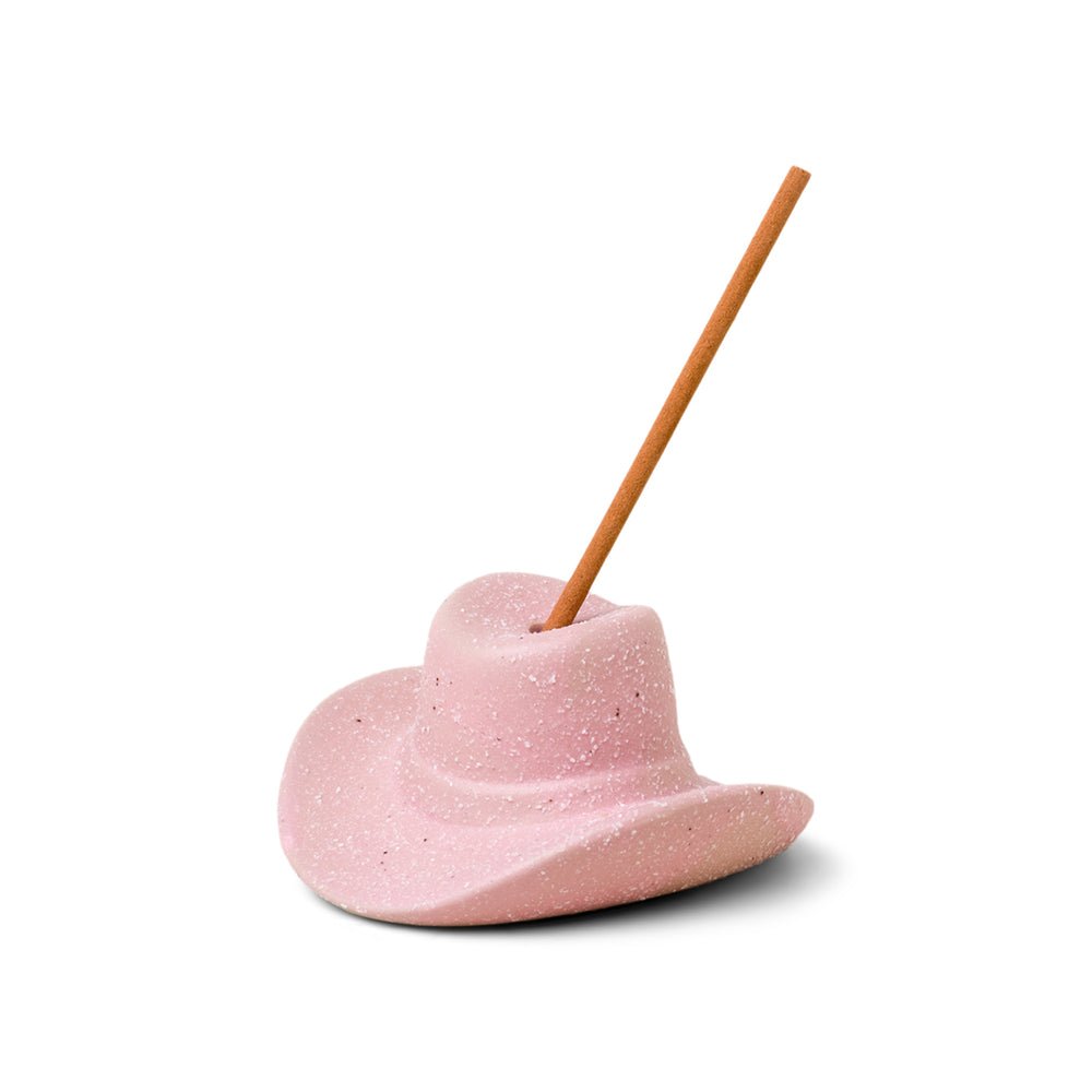 The Paddywax Pink Cowboy Hat Ceramic Incense Holder exudes rustic charm and a Western vibe. This speckled incense holder elegantly displays a single stick against a plain white background, blending seamlessly into any space.