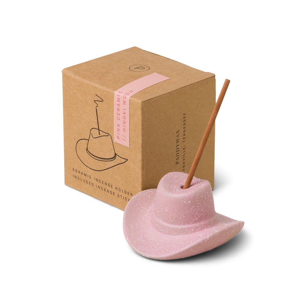 The Paddywax - Pink Cowboy Hat Ceramic Incense Holder offers a Western charm with a serenely burning incense stick, resting by its labeled brown Hinoki wood box.