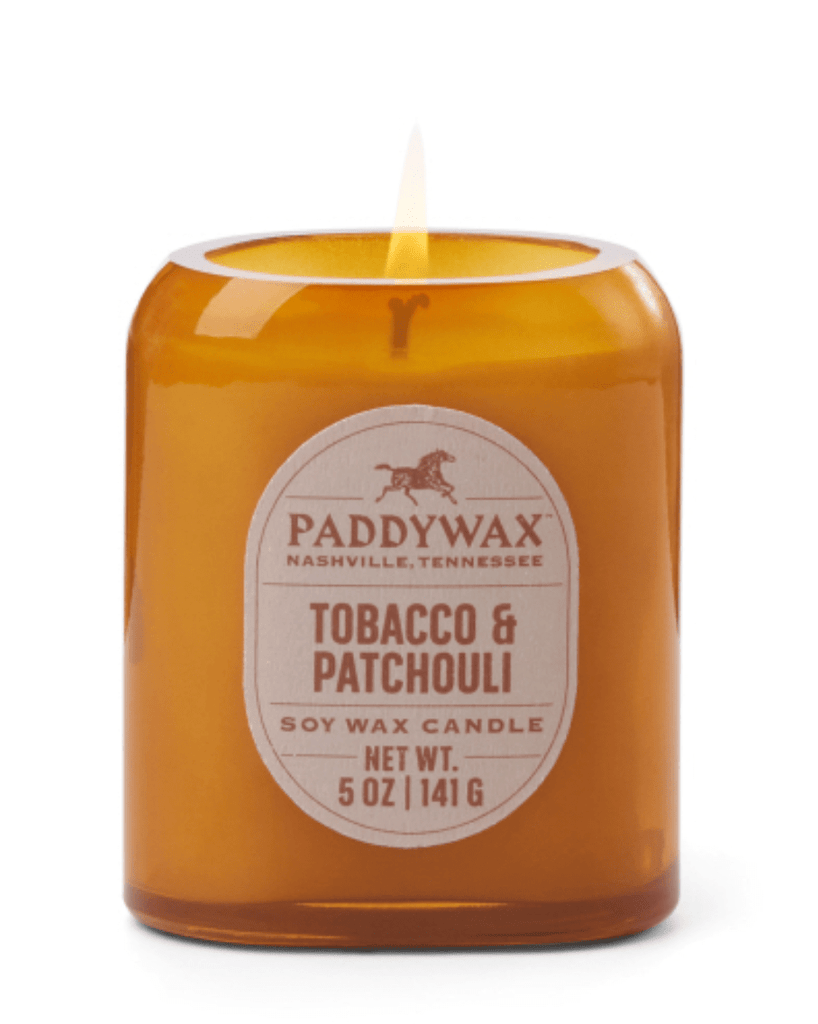 The Paddywax - Vista Tobacco & Patchouli Amber Glass Candle, weighing 5 oz (141 g), exudes a warm Western fragrance. Its vintage-inspired soy wax flame dances beautifully against the tonal glass finish, and its labeled Paddywax Nashville, Tennessee.