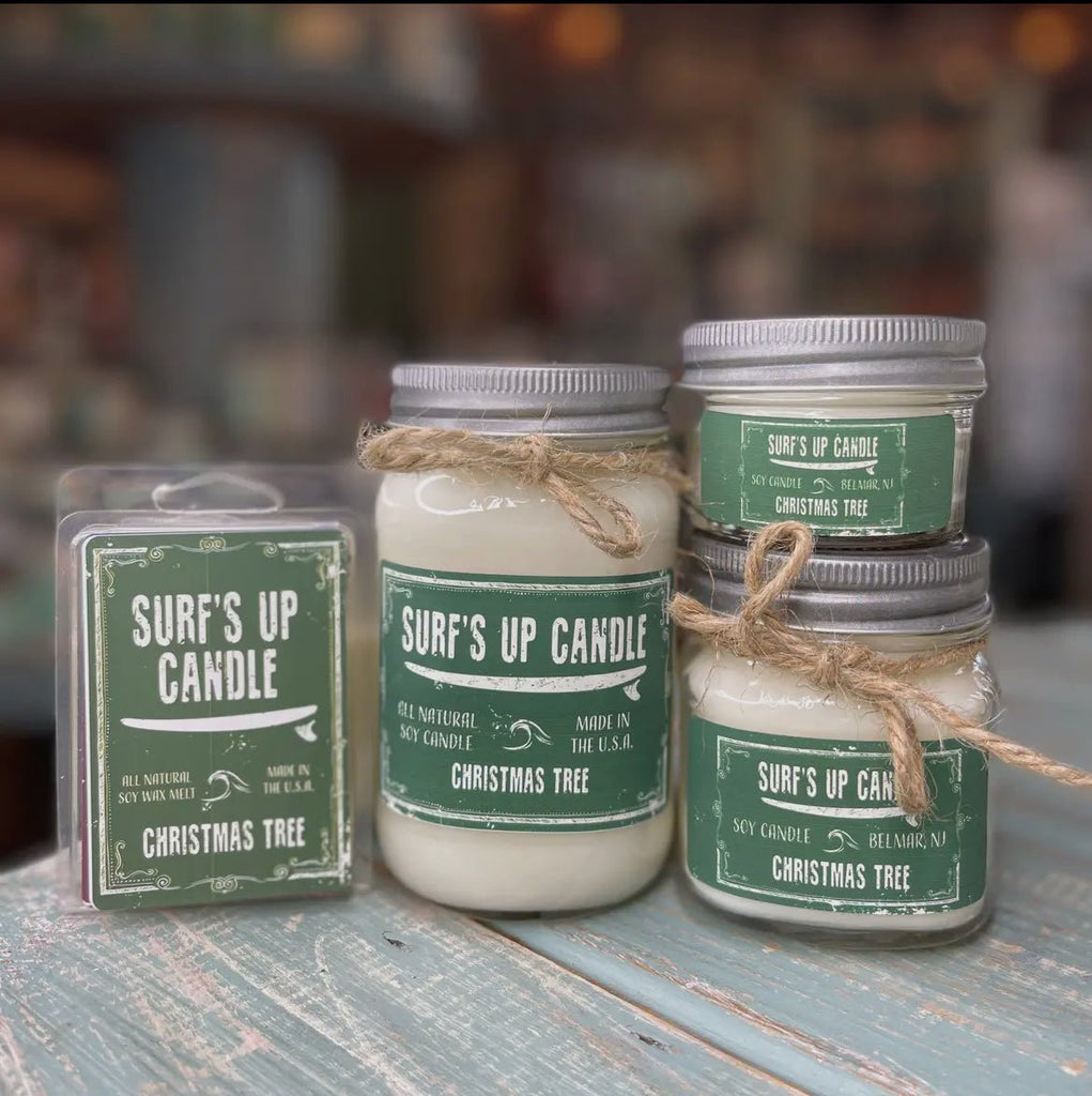 The Surf’s Up - Christmas Tree Mason Jar Candle by Surfs Up Candles is crafted with natural soy wax and includes reusable Mason jars, a wax melt package with green labels, and rustic twine accents, beautifully displayed on a wooden surface.