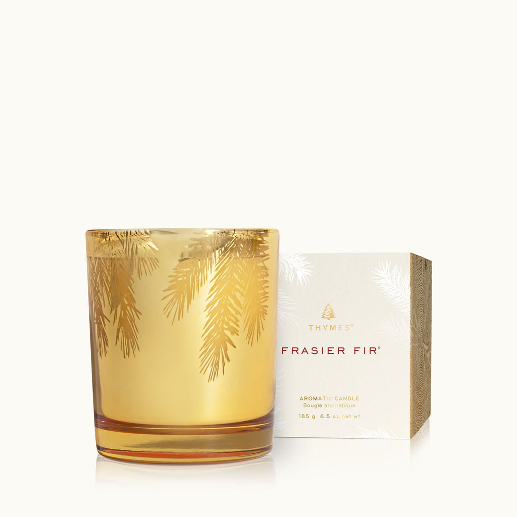 The Thymes Frasier Fir Gilded Gold Candle, 6.5oz, features a Siberian Fir scent with a gilded holder adorned in pine branch patterns and a matching white box with gold accents.