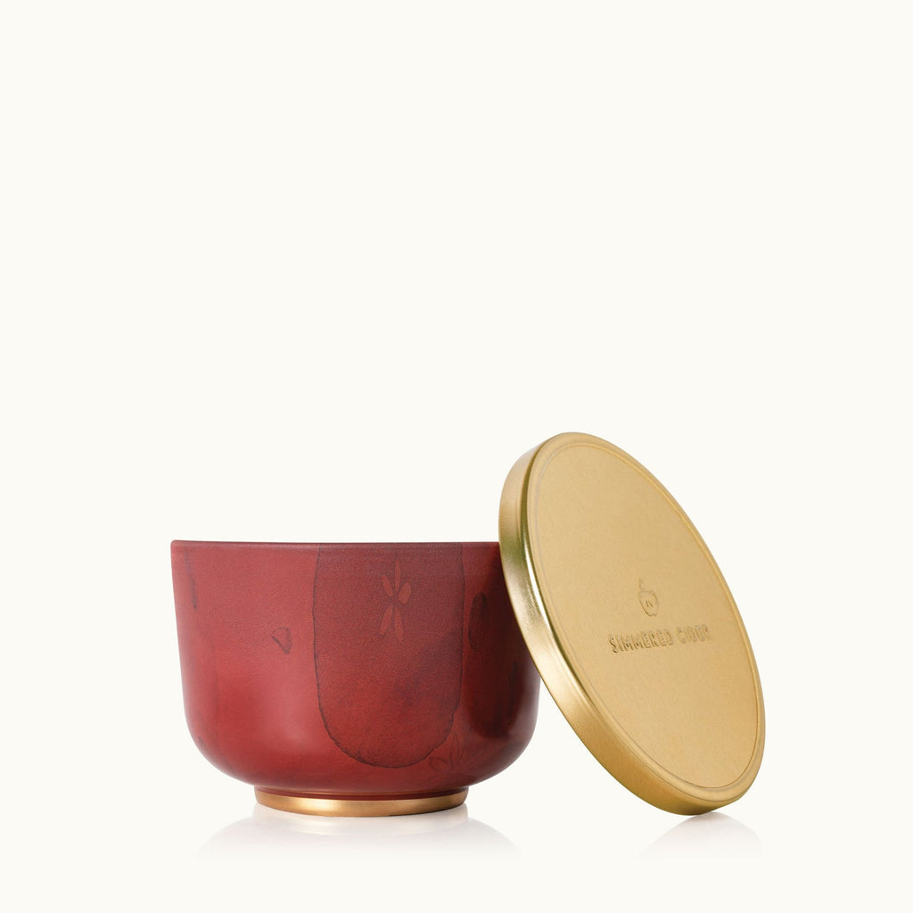 The Thymes - Simmered Cider Candle Tin with Gold Lid by Thymes features a red tin with a gold lid, evoking the cozy mulled apple fragrance of Simmered Cider—like a portable home scent, beautifully set against a plain white background.