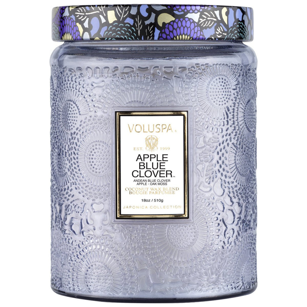 The Voluspa - Apple Blue Clover Large Jar 18oz Candle displays intricate floral designs and a vibrant lid, part of the Japonica Collection. It uses a coconut wax blend for an excellent fragrance throw, featuring the Andean Blue Clover aroma.