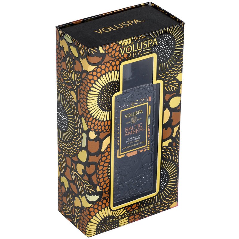 A box of Voluspa Baltic Amber Ultrasonic Diffuser Fragrance Oil infused with Vanilla Orchid showcases ornate floral patterns in gold, black, and brown, highlighting the brand name and product information.