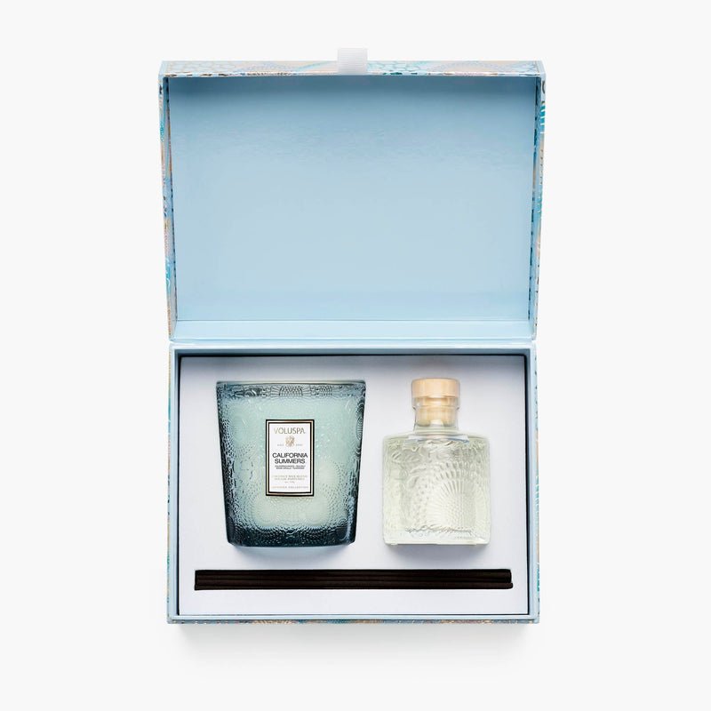 The Voluspa - California Summers Getaway Duo Gift Set features a textured glass Coconut Wax Candle and a Reed Diffuser in a clear bottle, all nestled in a light blue box—capturing the essence of refreshing California Waves.