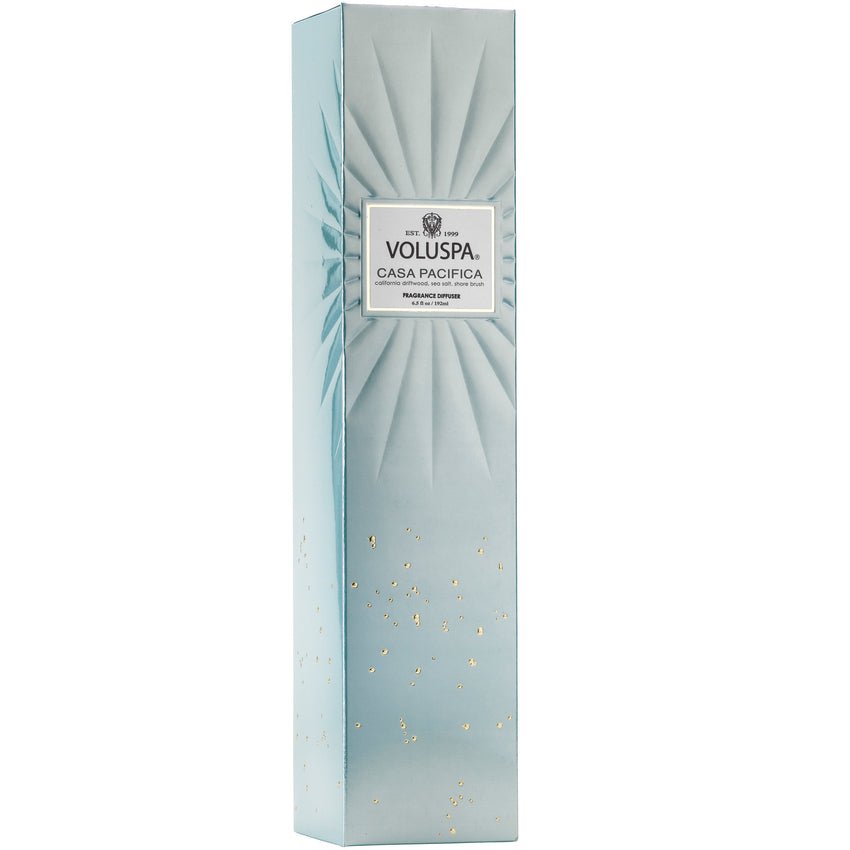 A tall, elegant light blue rectangular box with a sunburst design and golden flecks at the bottom holds a soothing scented reed diffuser labeled Voluspa - Casa Pacifica 192ml Reed Diffuser.