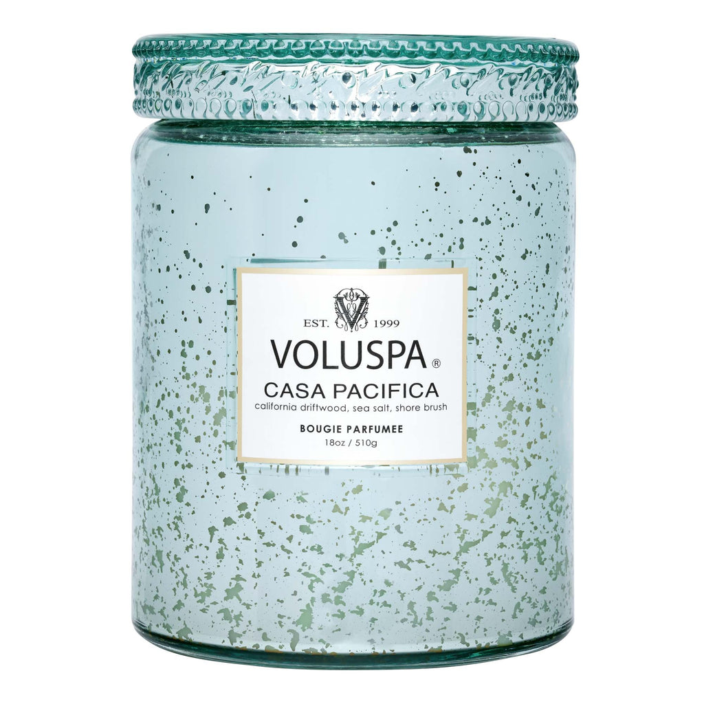 The Voluspa - Casa Pacifica Large Jar 18oz Candle features a light blue speckled glass and emits California driftwood and sea salt scents, crafted from a coconut wax blend.