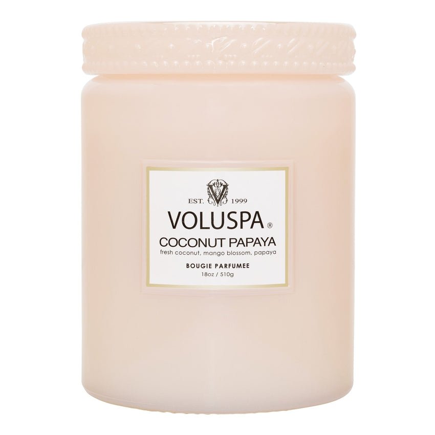 The Voluspa Coconut Papaya Large Jar 18oz Candle in light pink textured glass features notes of fresh coconut, mango blossom, and papaya, offering a tropical fruit aroma. Made with an 18oz coconut wax blend, it brings an island escape to your home.