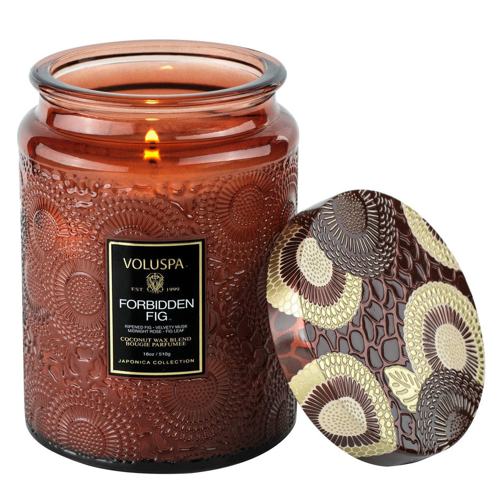 The Voluspa - Forbidden Fig Large Jar 18oz Candle features a textured amber glass jar with a decorative lid in gold and brown floral design, crafted from creamy coconut wax infused with the warm scent of ripened fig.