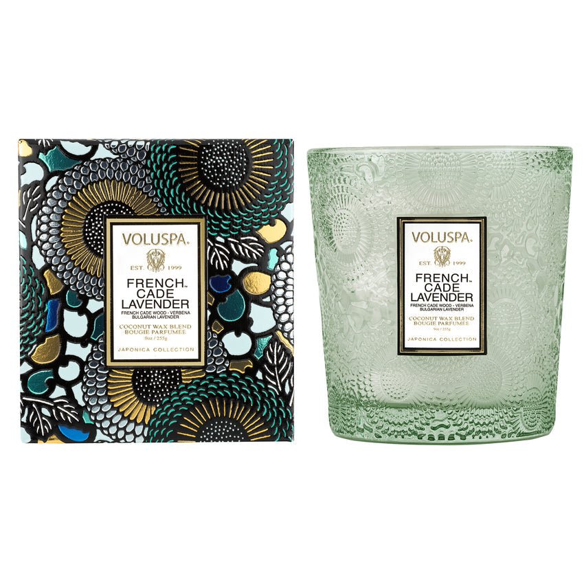 The Voluspa French Cade Lavender Classic 9oz Candle features a coconut wax blend in a textured green glass jar, paired with a floral-patterned box accented with gold and matching label.