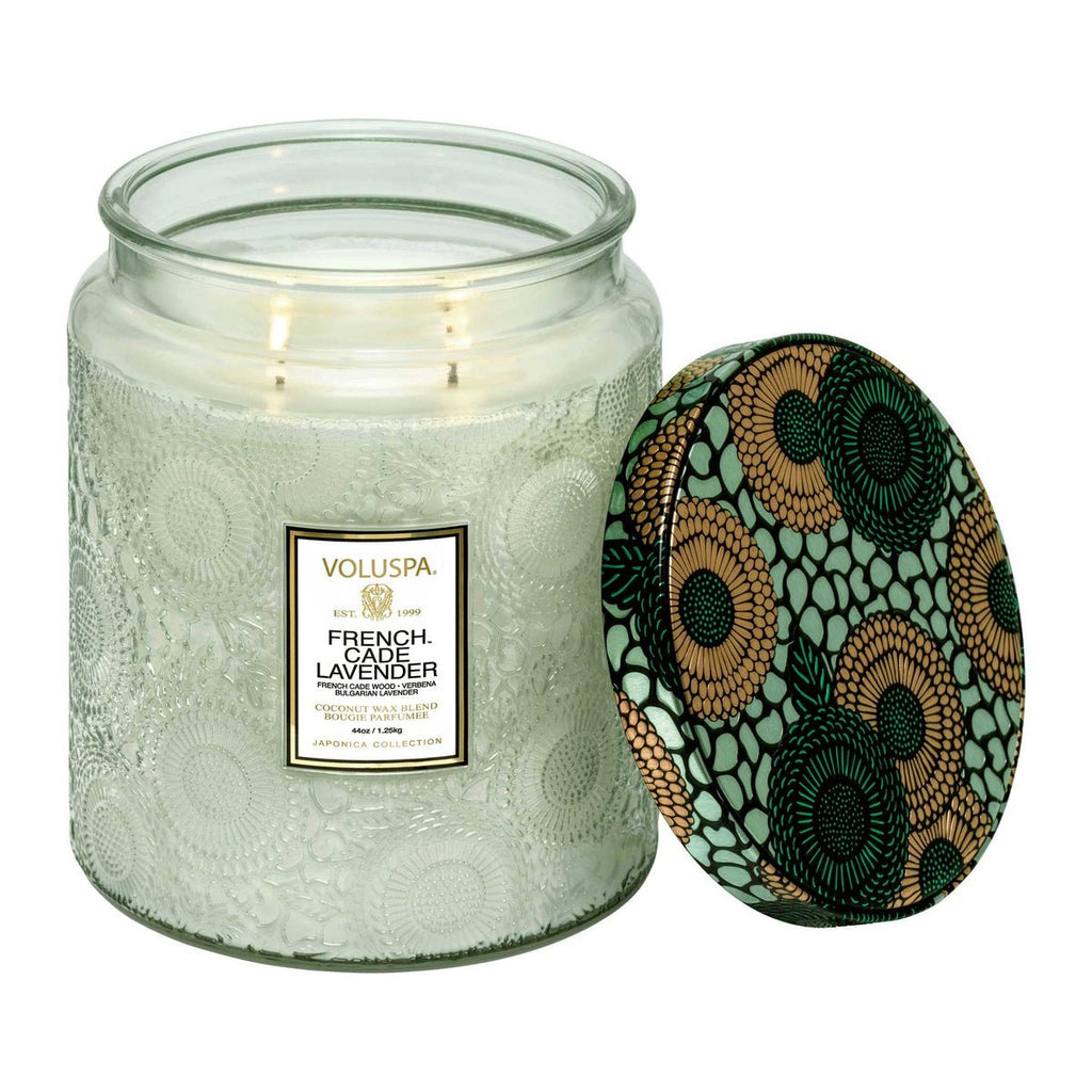 The Voluspa - French Cade Lavender Luxe Jar 44oz Candle features a textured glass jar with a decorative lid showcasing a green, black, and gold floral pattern. It emits soothing lavender and French cade wood scents and is crafted from coconut wax for a clean burn.