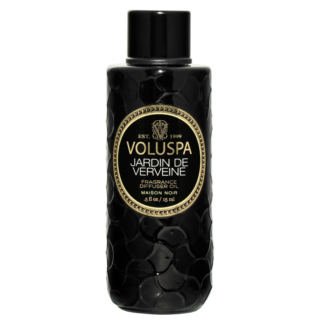 The Jardin De Verveine Blanc Ultrasonic Diffuser Fragrance Oil by Voluspa features a black, textured 5 fl oz bottle adorned with a gold-accented label and black cap, infused with verbena and lemongrass.