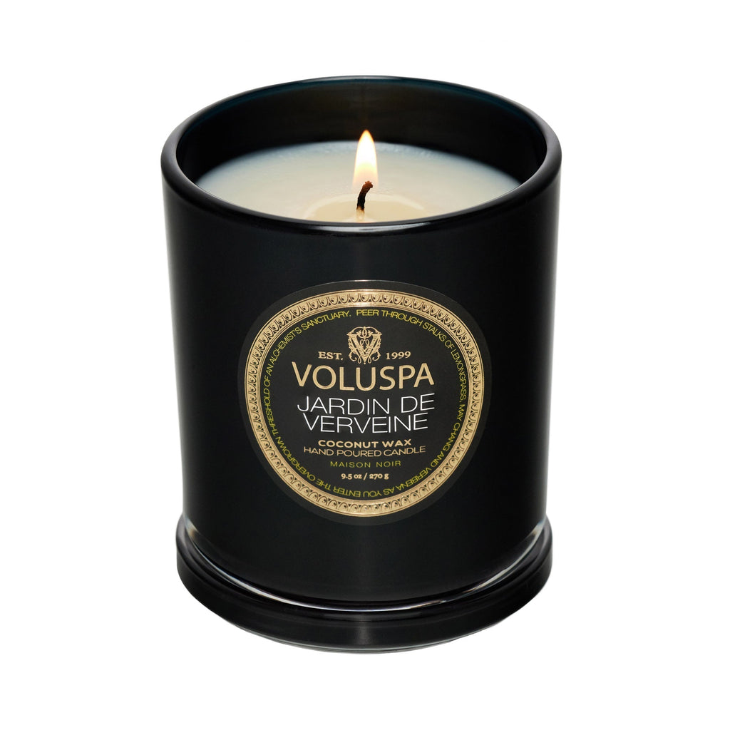 The Voluspa Jardin De Verveine Classic Candle, 9.5oz, offers a strong fragrance throw with soothing lemongrass tones. Its sleek black container features a gold and black label and is crafted from a coconut wax blend.