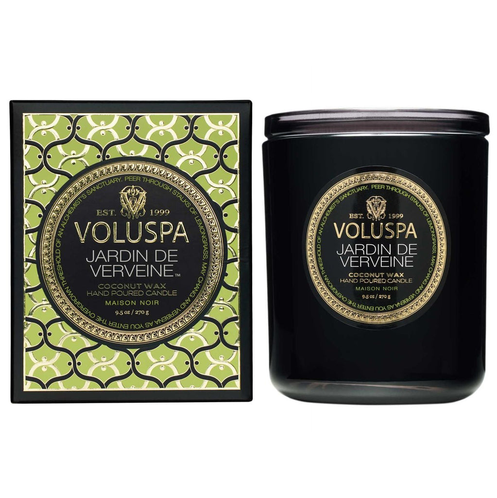 The Voluspa - Jardin De Verveine Classic Candle 9.5oz, featuring a green and black decorative box, boasts an impressive fragrance throw. Crafted from a coconut wax blend and hand-poured, this Maison Noir collection piece sits in a dark container that matches the design.