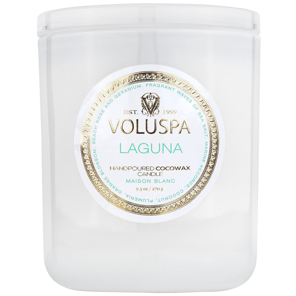 The Voluspa Laguna Classic Candle 9.5oz, from the Maison Blanc collection, features a metallic gold and white label with decorative edges and is hand-poured with a cocowax blend, offering an impressive fragrance throw.