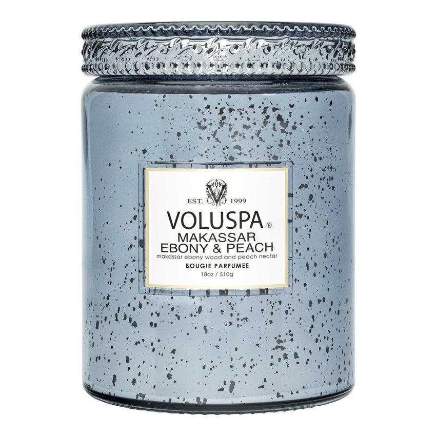 The Voluspa Makassar Ebony & Peach Large Jar 18oz Candle features a speckled blue design with a silver lid. Made from a coconut wax blend, it holds 510 g of aromatic bliss in a vintage-inspired jar.