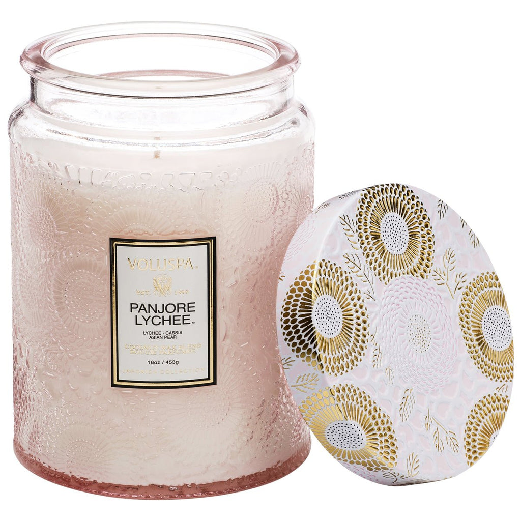 Voluspas Panjore Lychee Large Jar 18oz Candle, crafted from clean-burning coconut wax in cream color, features an embossed textured glass jar. The floral-patterned lid showcases gold and white motifs with a Panjore Lychee label.