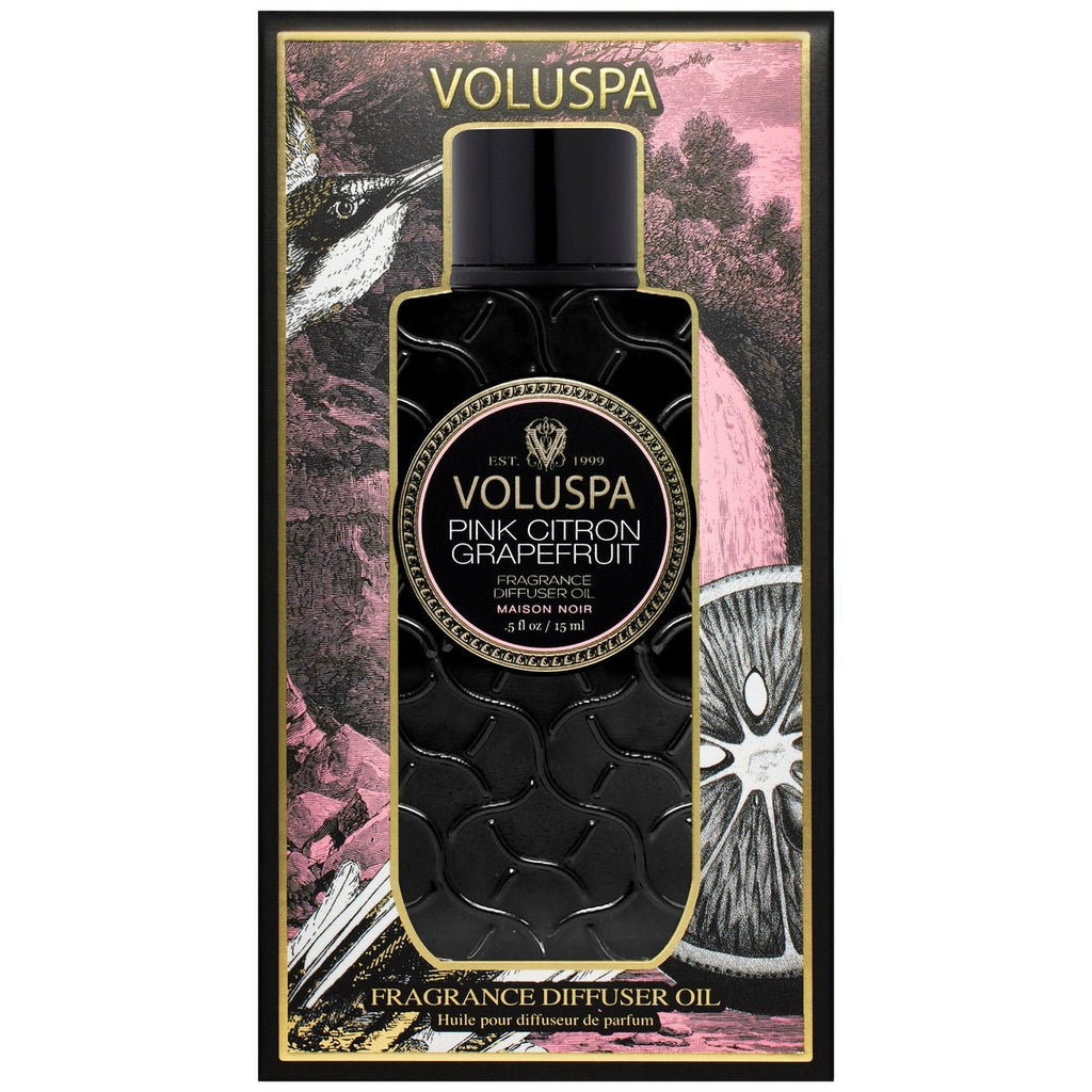 The Voluspa Pink Citron Grapefruit Ultrasonic Diffuser Oil features textured black packaging. The decorative box, embellished with pink and black designs and fruit illustrations, pairs beautifully with the vibrant essential oil scent.