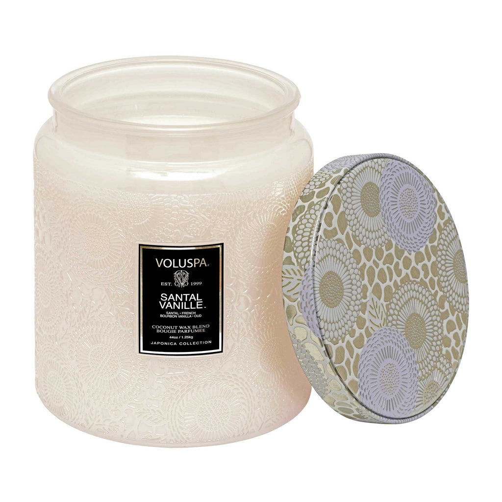 The Voluspa - Santal Vanille Luxe Jar 44oz Candle features an intricate floral design on the jar and a geometric floral lid. Made from a luxurious coconut wax blend, the unused off-white candle offers soothing vanilla scents.