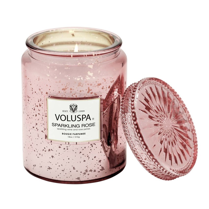 The Voluspa Sparkling Rose Large Jar 18oz Candle features a pink jar with ornate lid and reflective speckles, releasing a delicate floral aroma when lit to enchant any room.