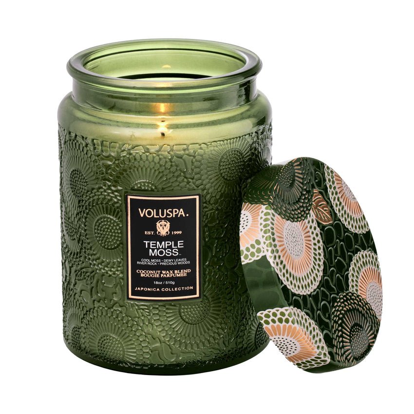 The Voluspa - Temple Moss Large Jar 18oz Candle features a coconut wax blend in an embossed green glass jar. The floral lid complements the design, and it offers an exceptional fragrance throw as part of Voluspas Japonica Collection.