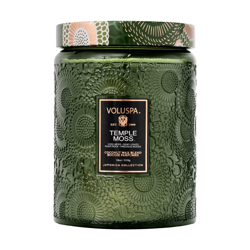 The Voluspa - Temple Moss Large Jar Candle, part of the Japonica Collection, features an 18oz coconut wax blend in an embossed glass jar, offering intricate patterns and an exceptional fragrance throw. The lid complements the exquisite design.